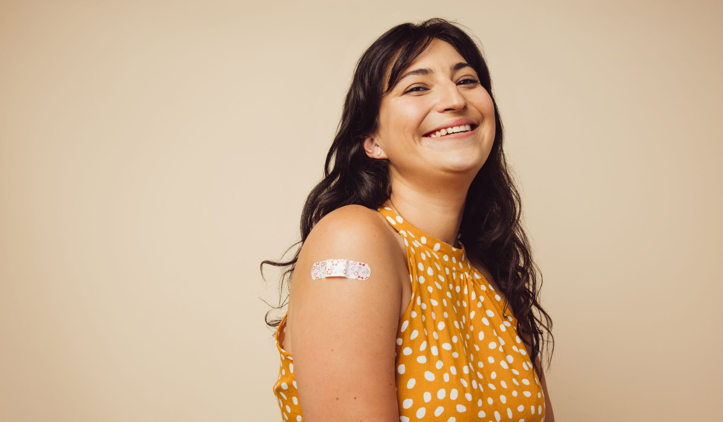 Woman with an adhesive bandage on her arm smiling at the camera