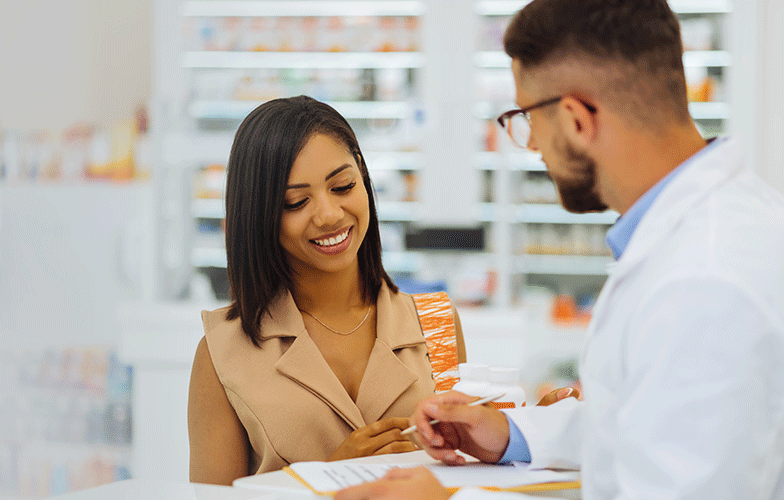 A smiling customer looking at paperwork while talking to a pharmacist
