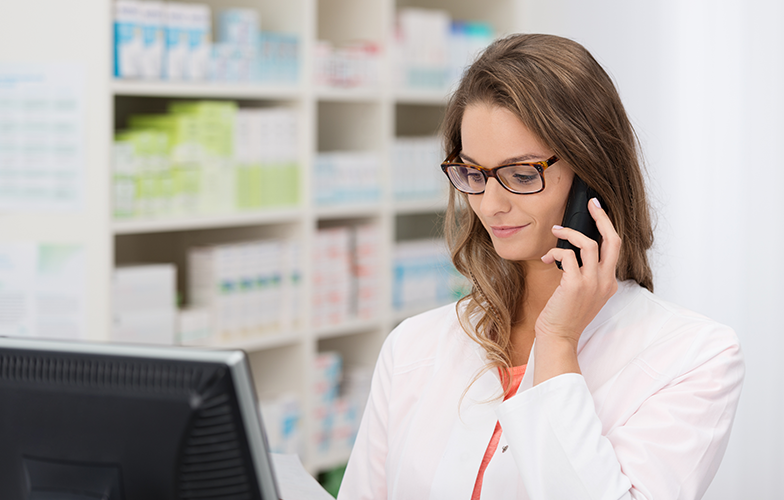 Female pharmacist talking on the phone looking at a computer screen